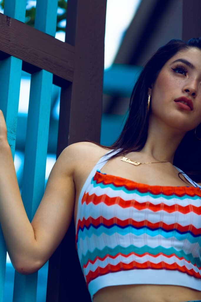 Plan poitrine d'un modèle féminin à la chevelure brune qui porte un débardeur de couleur bleu rouge et blanc