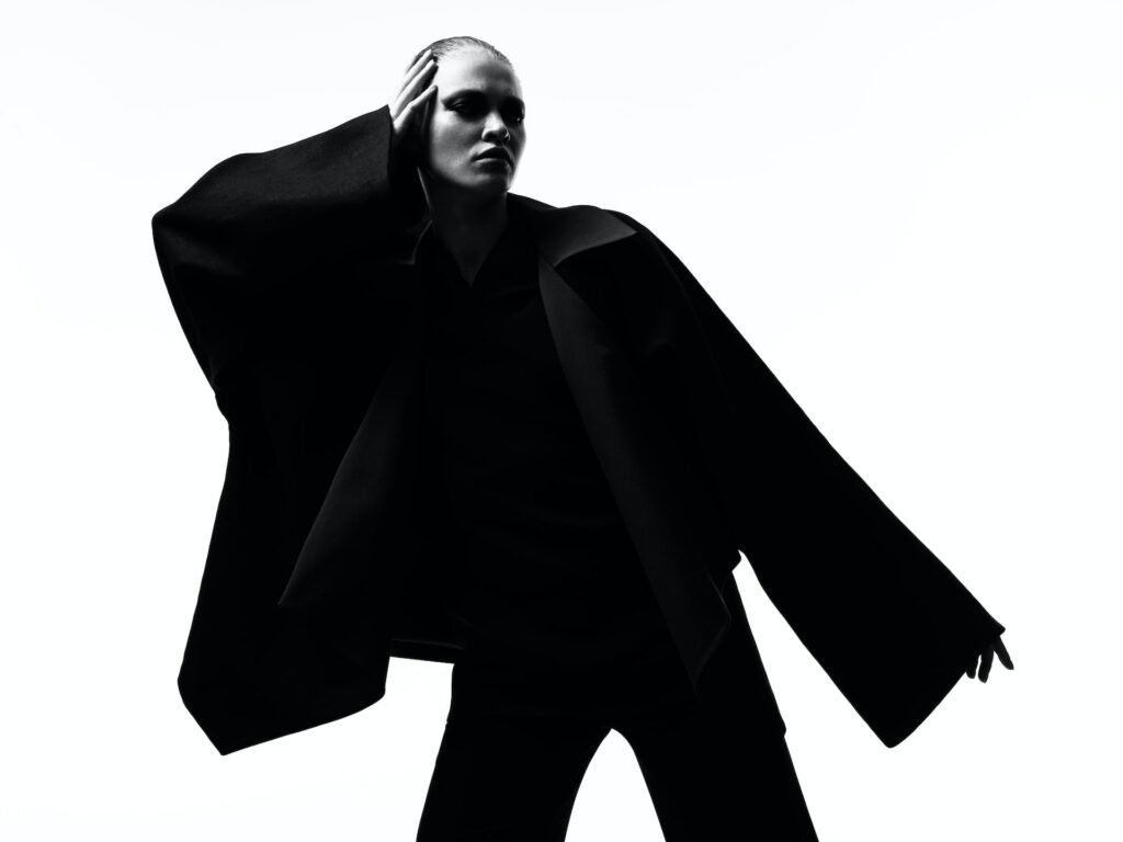 Plan général en noir et blanc d'un top model vêtu de noir dans un style mode chic