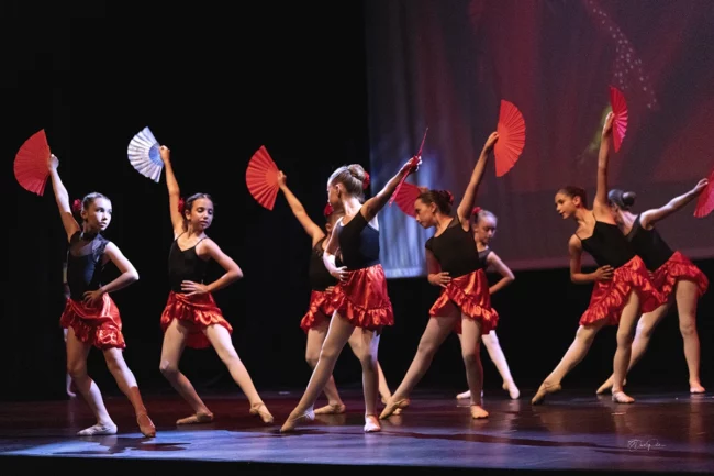 Groupe de jeunes danseuses classiques en costumes élégants posant ensemble avec harmonie