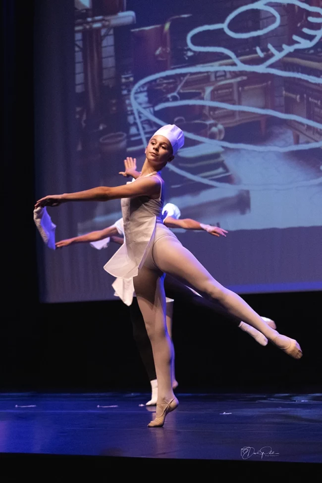 Lucille Polet danse avec élégance en costume blanc et toque de cuisinier