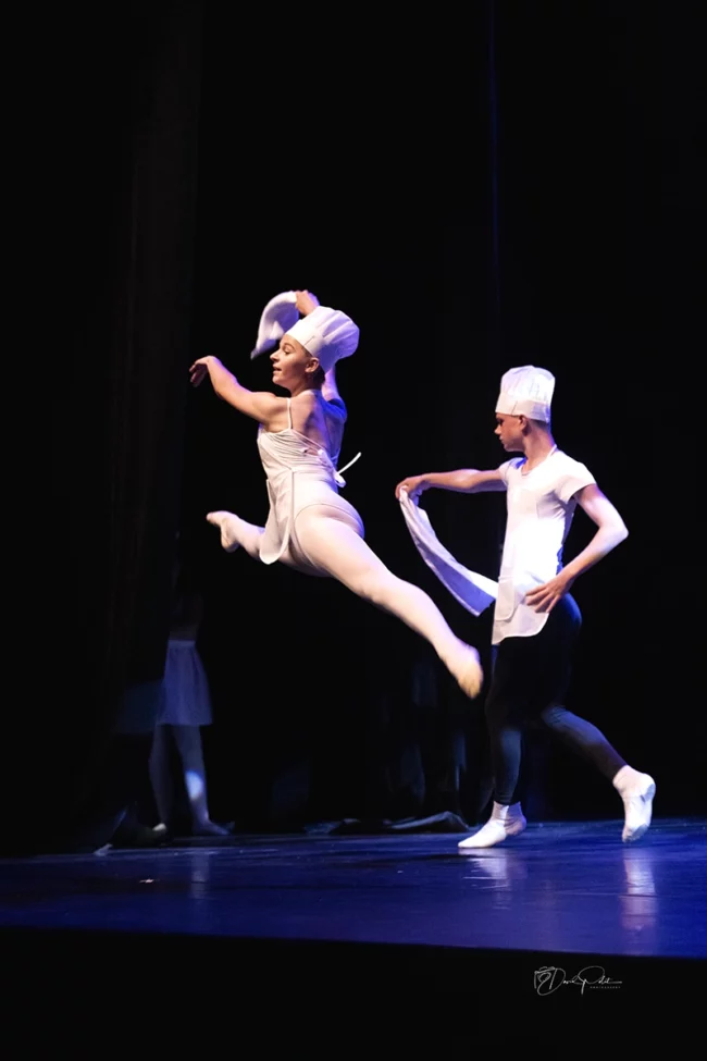 Groupe de danse classique en costume blanc et toque dans une chorégraphie