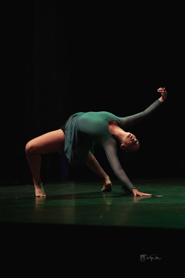 Danseuse modern jazz exécutant un solo éclairé par des lumières vertes captivantes
