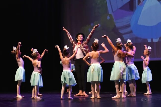 Le Chapelier partage la scène avec de jeunes danseurs en tenues soignées