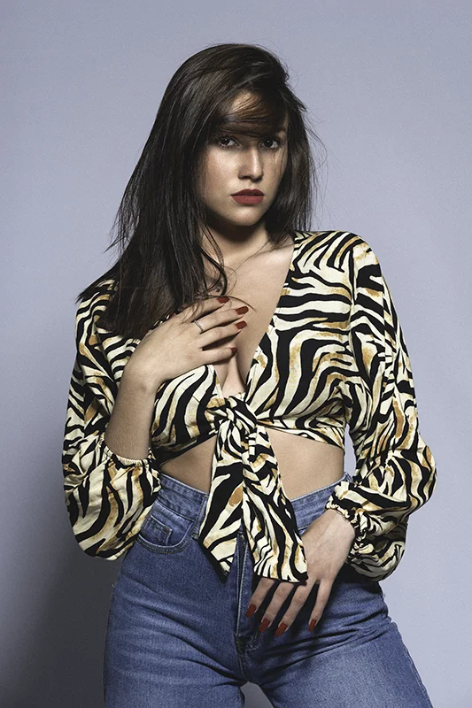 Portrait mode d’une femme en studio, vêtue d’un top imprimé zèbre et d’un jean. Photo réalisée par David Polet, photographe à Nice et Villeneuve-Loubet.