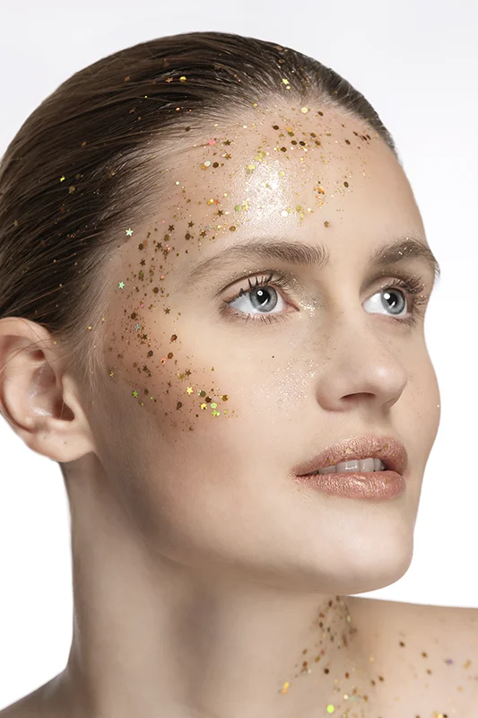 Portrait d’une femme au regard perçant, sublimée par des paillettes dorées. Photo par David Polet, photographe à Nice et Villeneuve-Loubet.