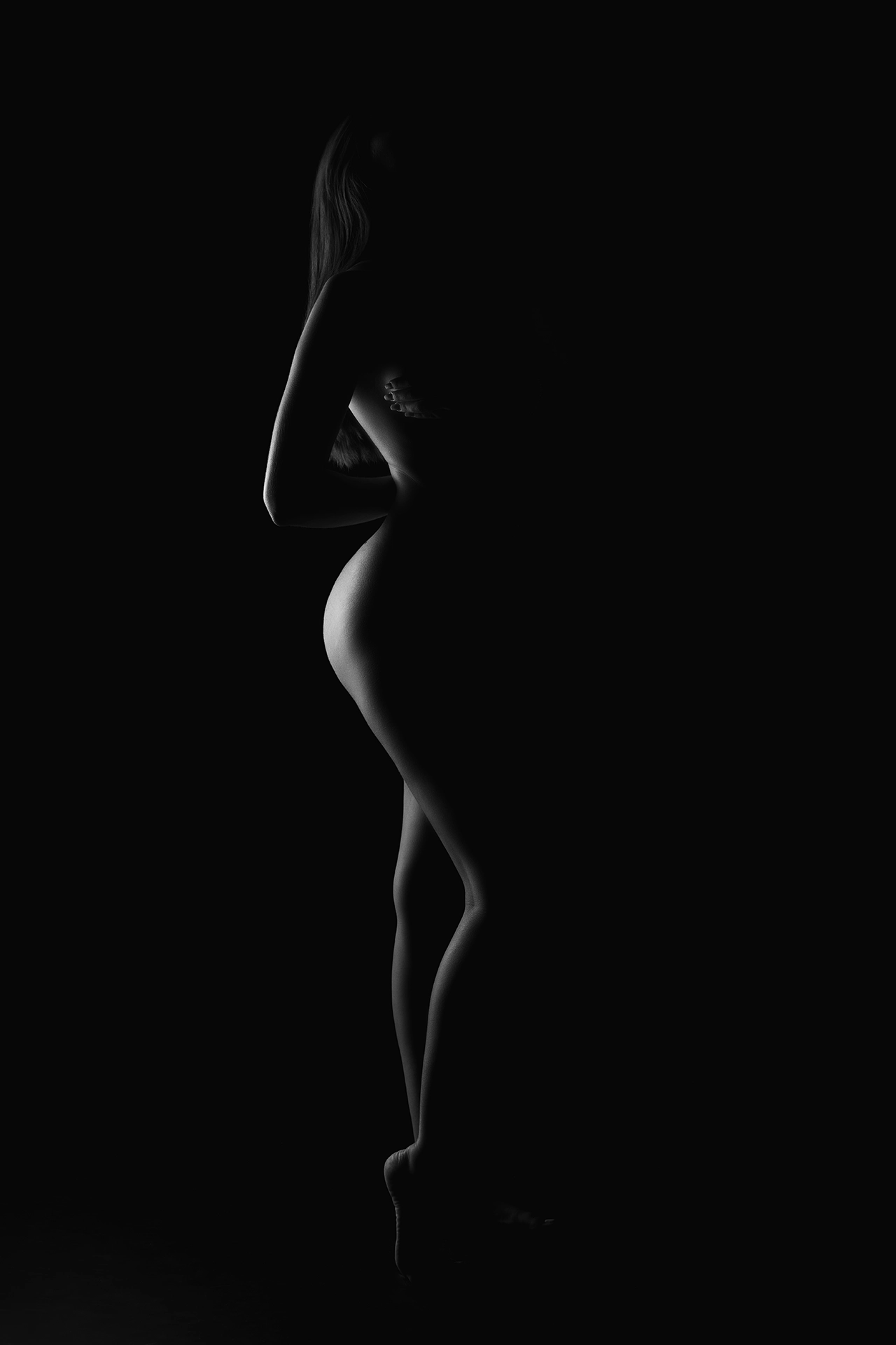 shoot-photo-nu-art-10 Silhouette féminine en clair-obscur, mise en valeur par un jeu subtil de lumières et d’ombres.