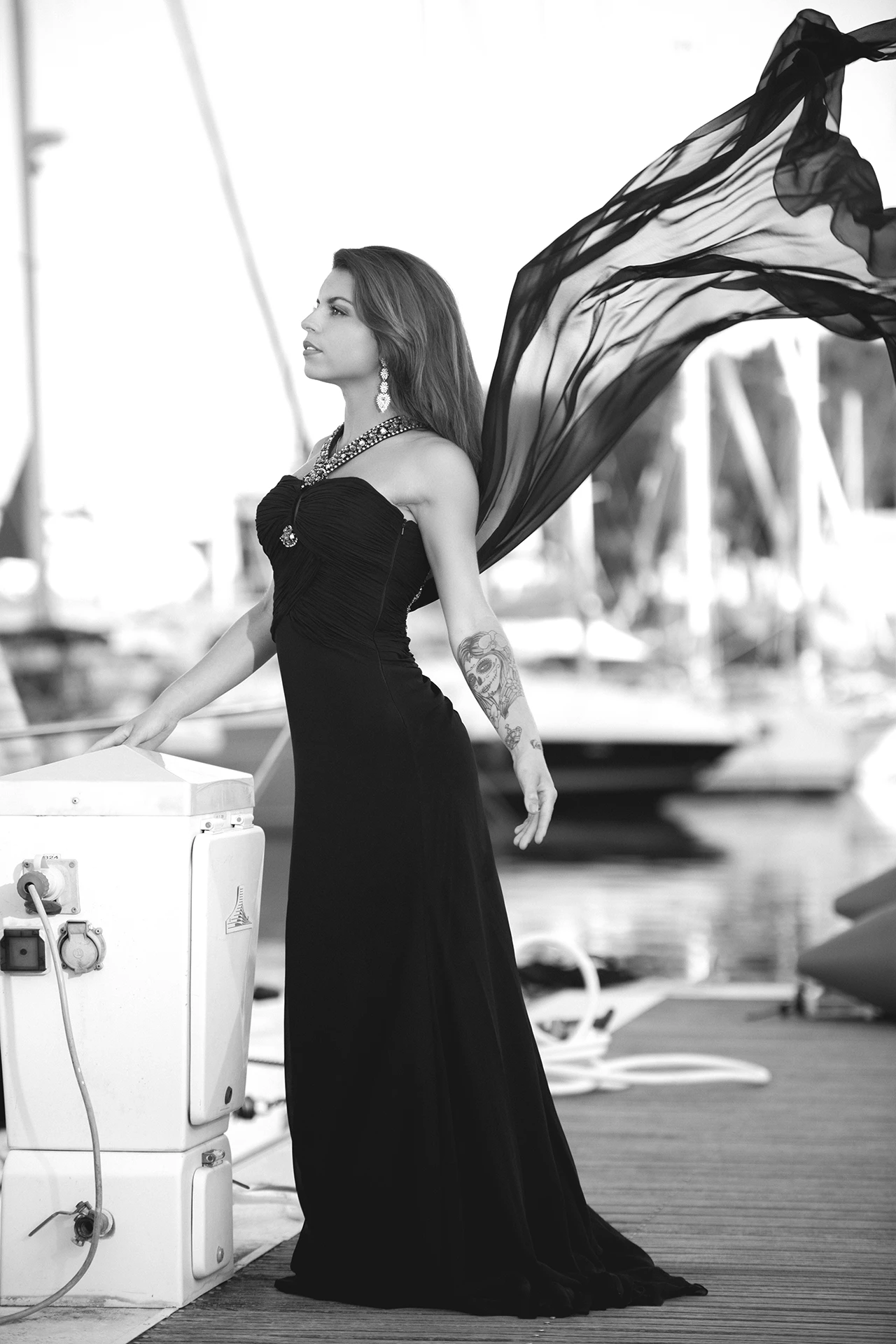 shooting-photo-villeneuve-loubet- Femme en robe de soirée sur un ponton à Villeneuve Loubet, voile flottant au vent, tatouages visibles. Shooting photo à Nice.
