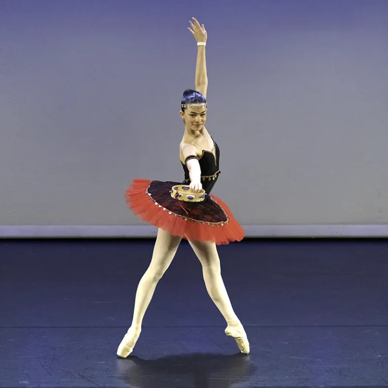 Danseuse classique sur scène, tutu rouge et noir, pose en pointes bras levé – photographe de danse Nice