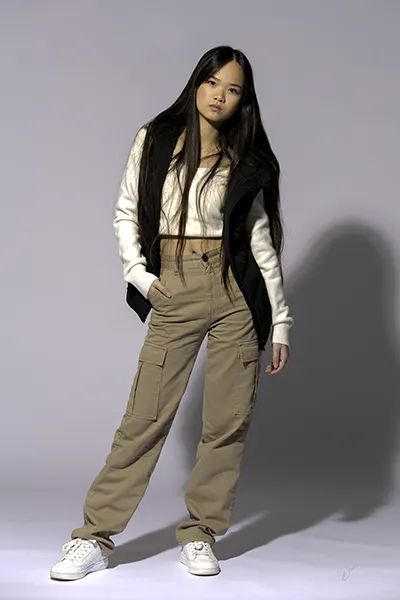 Portrait mode en studio : jeune modèle posant en pantalon cargo beige et look streetwear, signé David Polet Photography.