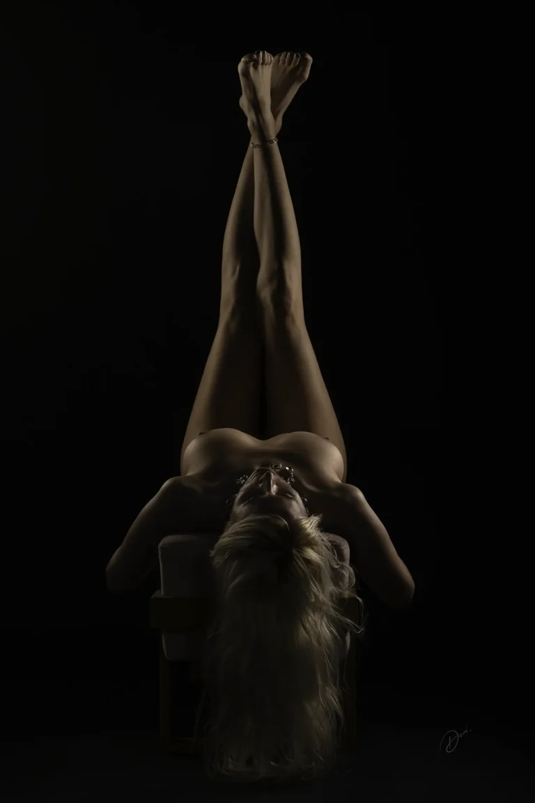 Nu artistique femme allongée en clair-obscur, jambes tendues, lumière sculptant le corps, séance photo nu artistique femme