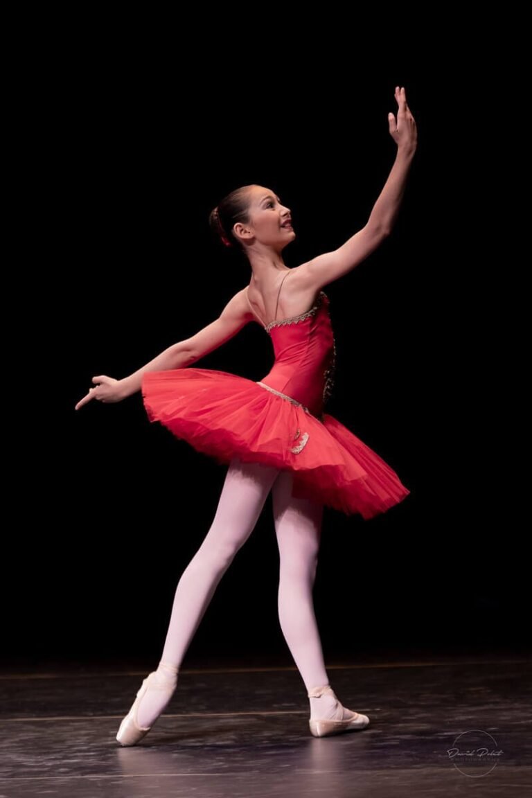 Danseuse classique en tutu rouge sur scène, photographe de danse Côte d’Azur, ballet élégant sur fond noir