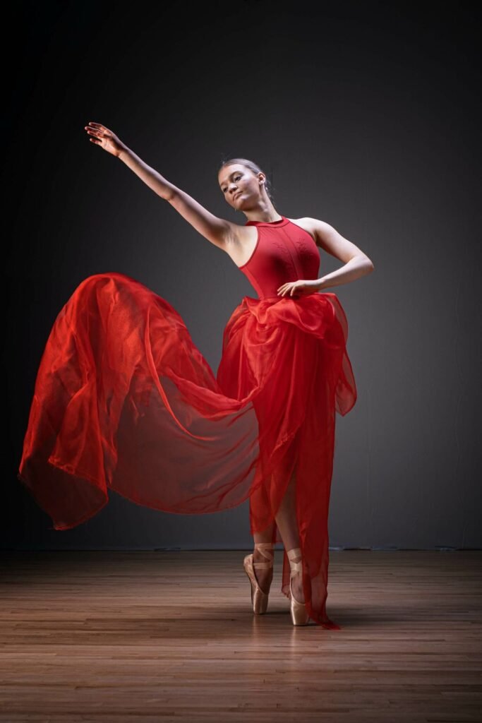 Danseuse classique en robe rouge, photographe de danse sur la Côte d’Azur, mouvement élégant en studio