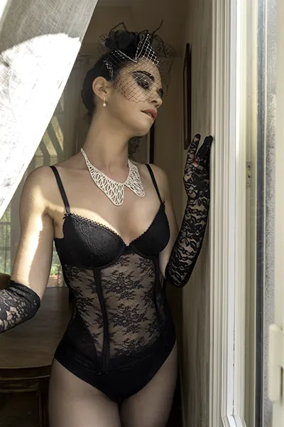 Portrait mode élégance rétro, modèle en lingerie noire dentelle et accessoires vintage près d’une fenêtre