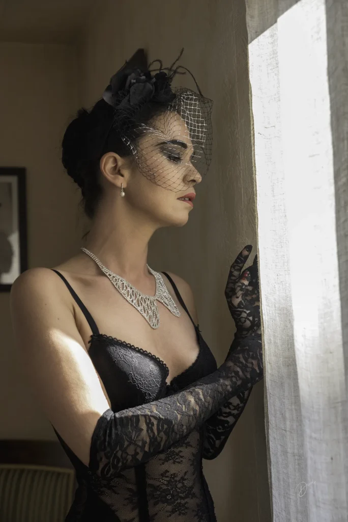 Portrait boudoir en lingerie noire près d’une fenêtre, lumière naturelle et élégance, shooting boudoir à Nice