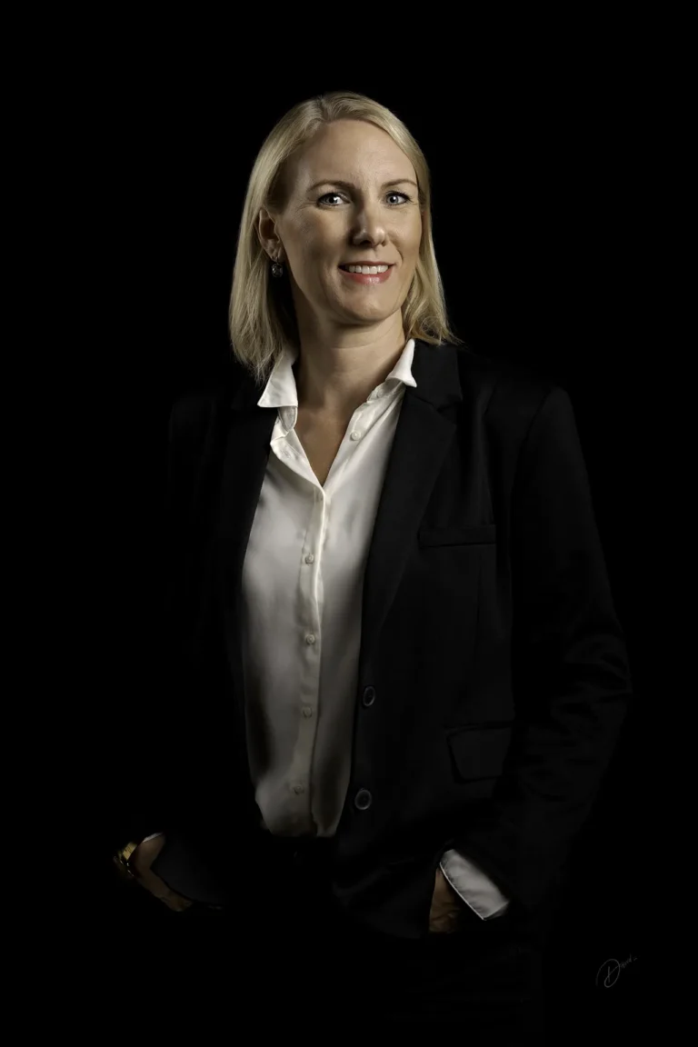 Portrait corporate en studio sur fond noir, femme souriante en tailleur noir et chemise blanche, éclairage professionnel — Villeneuve-Loubet