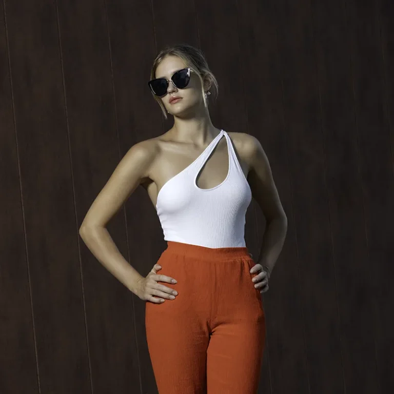 Portrait mode en extérieur, femme en top blanc asymétrique et pantalon rouge, lunettes noires – photographe de mode Nice