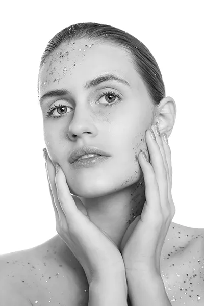 Portrait beauty avec paillettes or, maquillage lumineux et peau éclatante en studio, photographie beauté professionnelle.