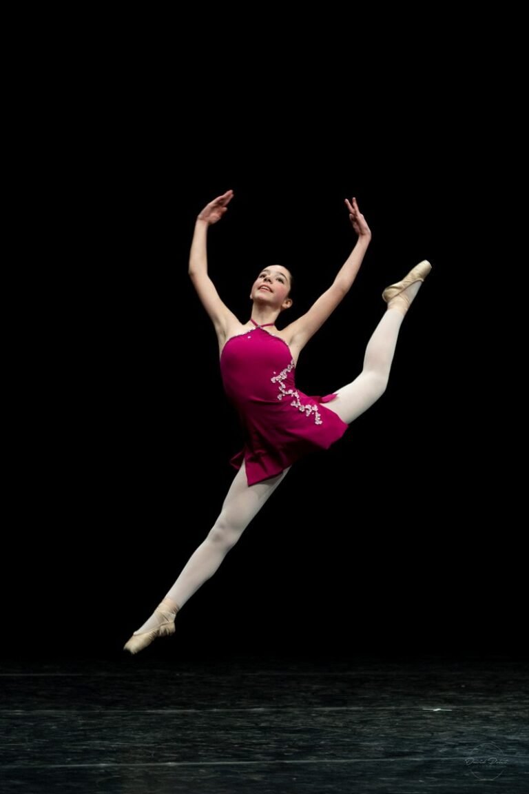 Danseuse en plein saut sur scène, photographe de danse Côte d’Azur, ballet artistique sur fond noir