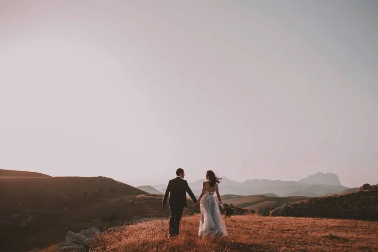 Couple de mariés marchant main dans la main au coucher du soleil, photographe de mariage dans les Alpes-Maritimes
