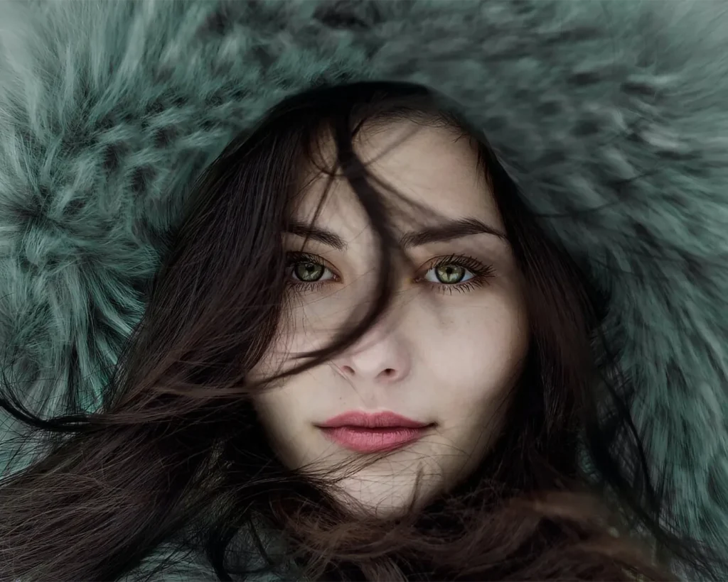 Portrait beauté d’un mannequin en capuche fourrure, regard vert, ambiance hiver en studio