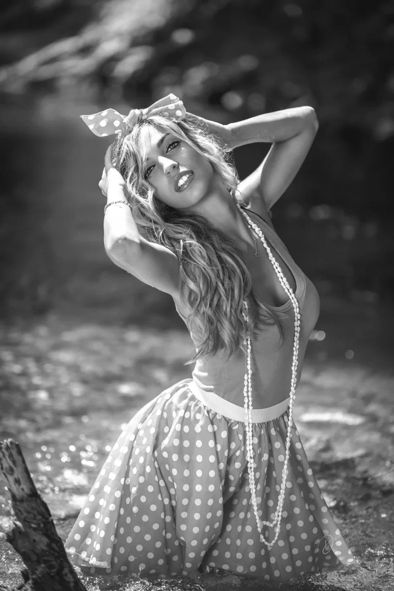 Portrait noir et blanc en extérieur, femme style rétro pin-up, mains dans les cheveux