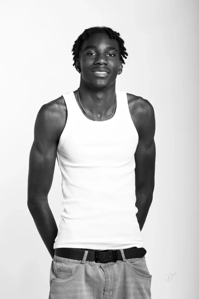 Portrait polas noir et blanc d’un mannequin homme en débardeur blanc, fond studio clair, sourire naturel