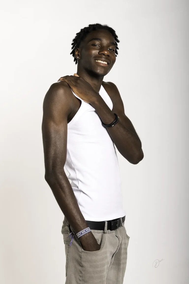 Portrait studio sur fond blanc, homme souriant en débardeur blanc, pose 3/4