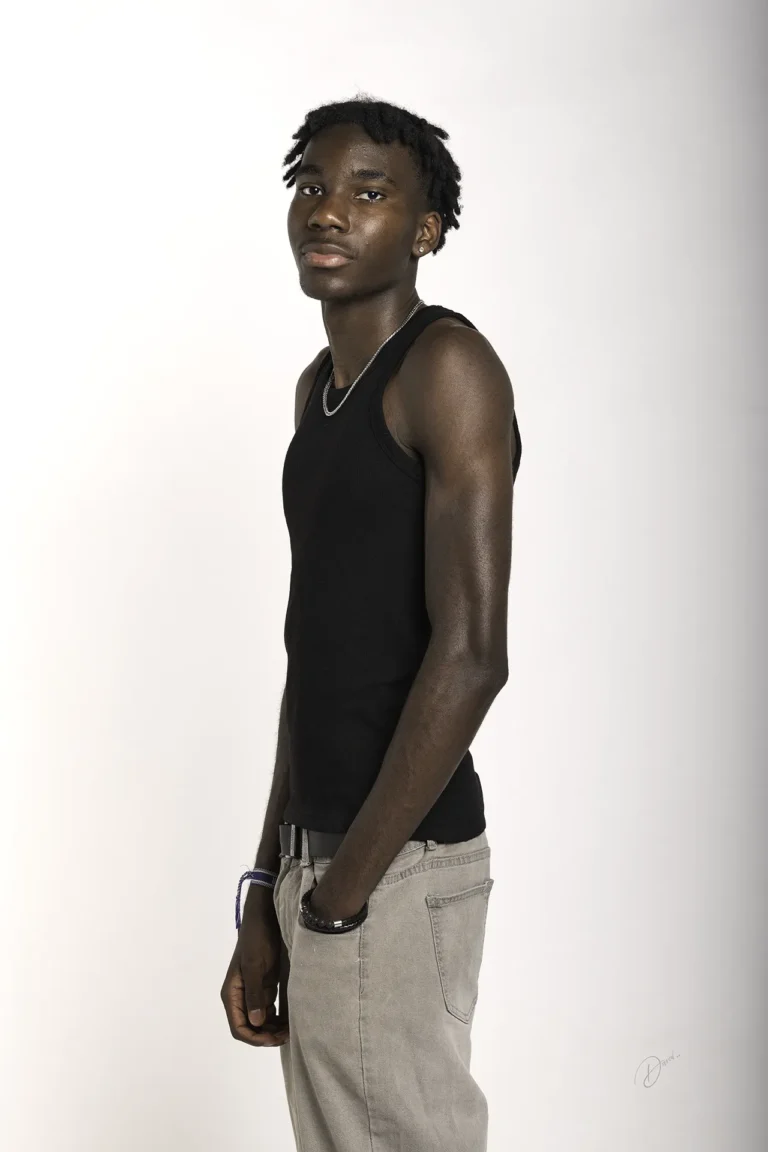 Séance photo polas en studio : homme en profil 3/4, débardeur noir et jean clair, fond blanc