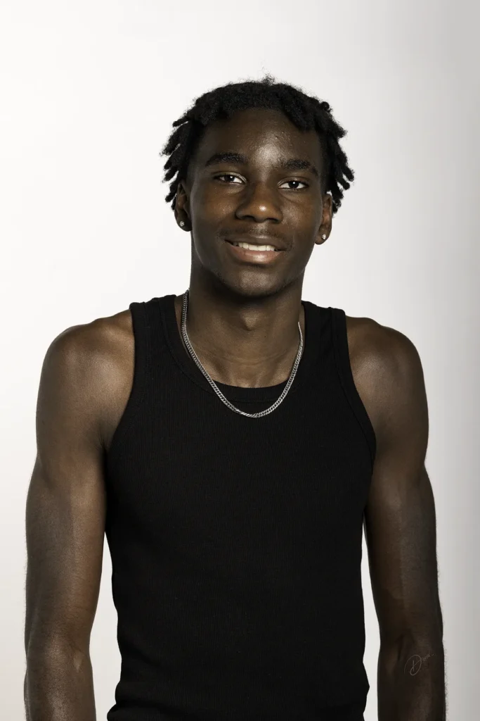 Séance photo polas en studio : portrait homme souriant, débardeur noir et chaîne, fond blanc