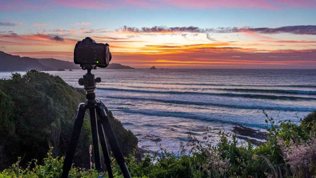 Photographe professionnel en extérieur avec appareil photo sur trépied au coucher du soleil