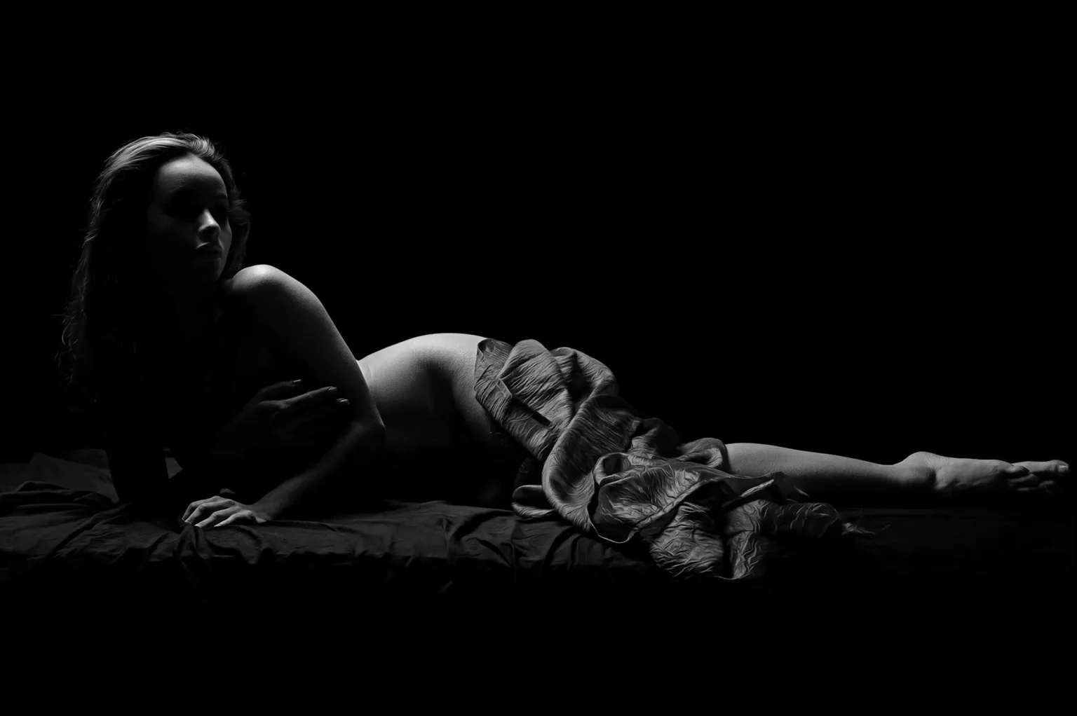 Nu artistique en studio avec pose allongée en noir et blanc et lumière clair-obscur