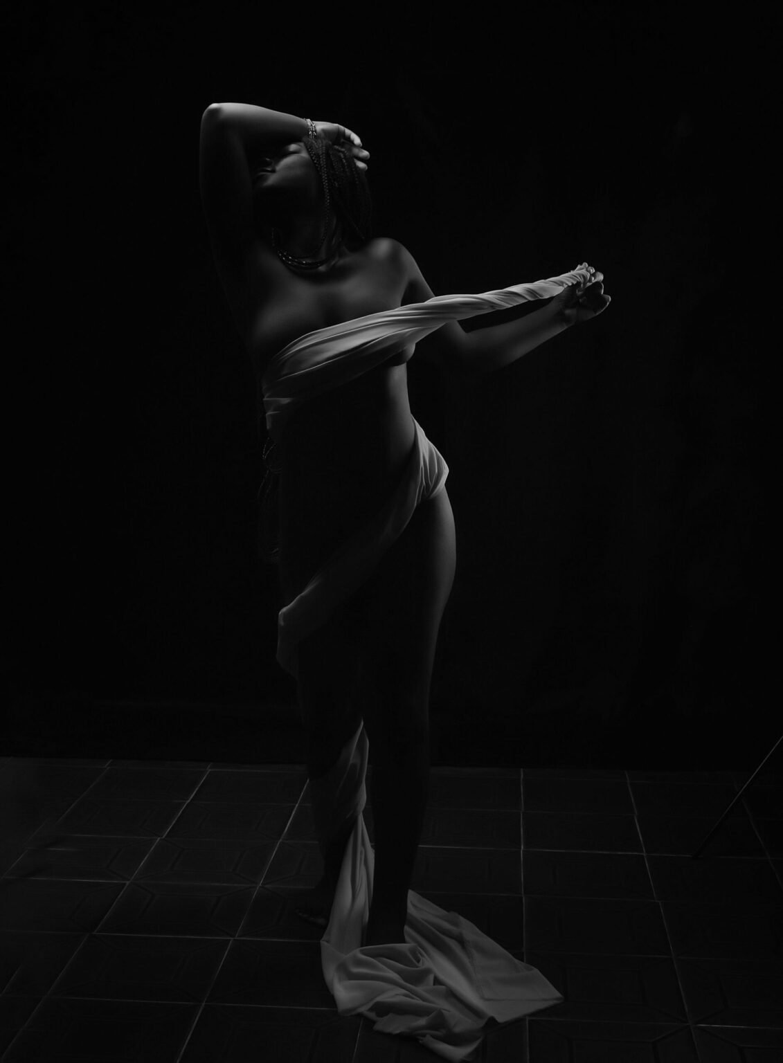 Photo de nu élégante avec tissu blanc en studio et lumière clair-obscur