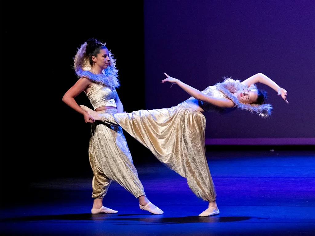 Deux danseuses en costumes dorés réalisant une figure à deux lors du spectacle Le Roi Lion du Studio Pirouette.